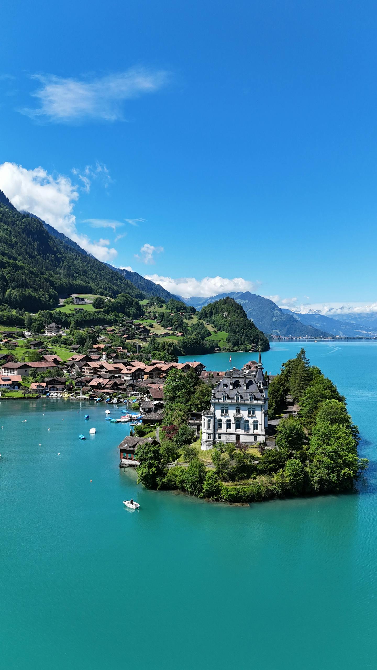 A picturesque villa nestled on an island in a vibrant turquoise lake surrounded by Swiss Alps.
